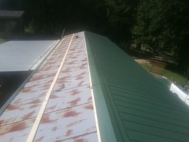 Old rusted panels beside newly installed green metal roofing — Wind Damage Roof Repair by Roofing Brothers in Vienna